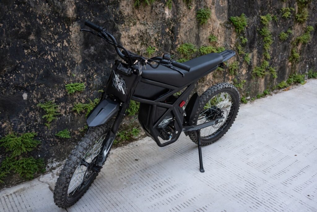 Black electric bike parked on an urban street against a wall with green foliage